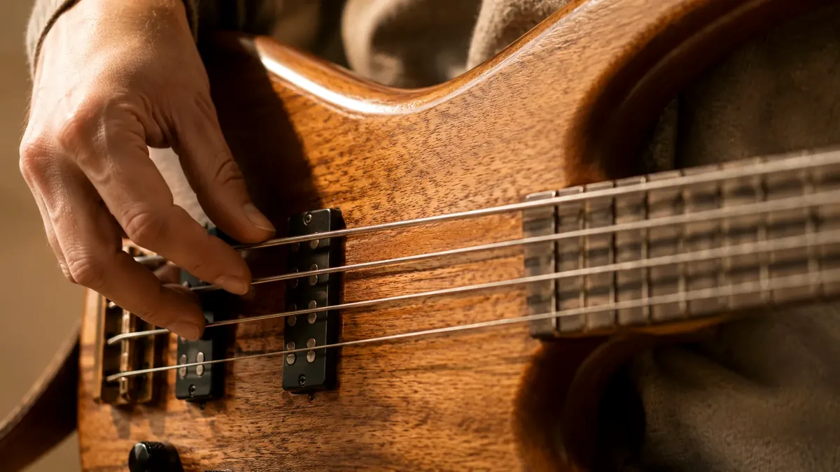 Rechterhand die de snaren van een basgitaar aanslaat